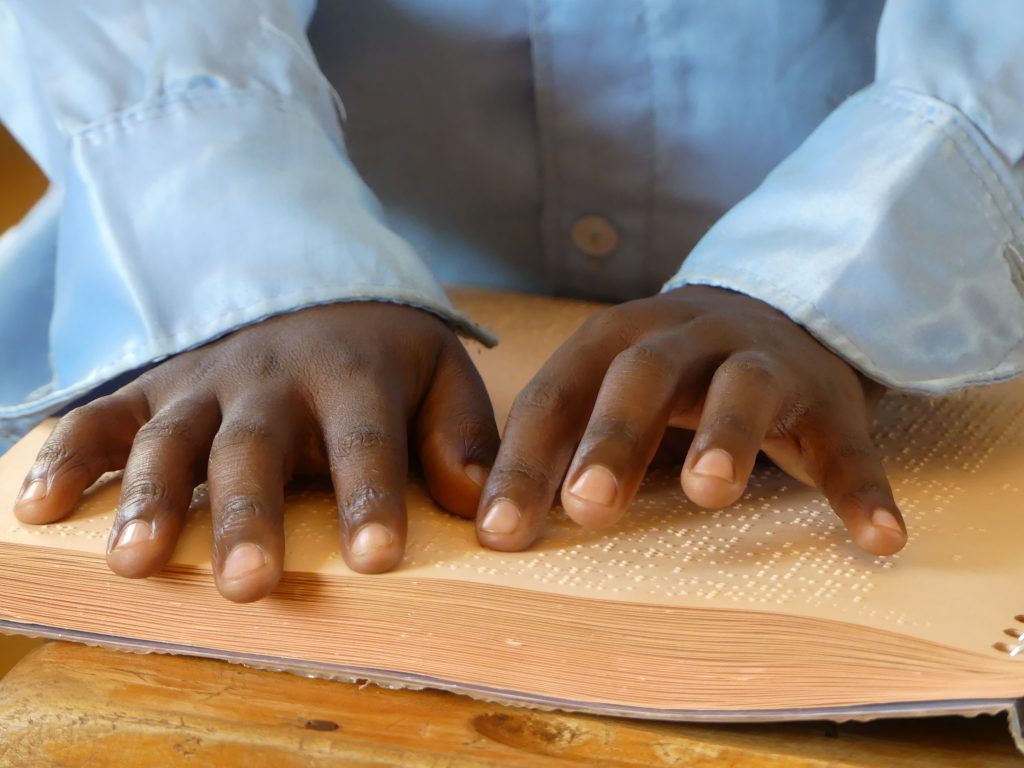 manos de niños leyendo braille