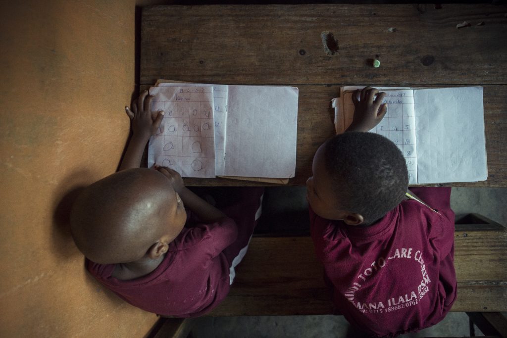 Dos niños escriben en libros escolares la foto está tomada desde arriba