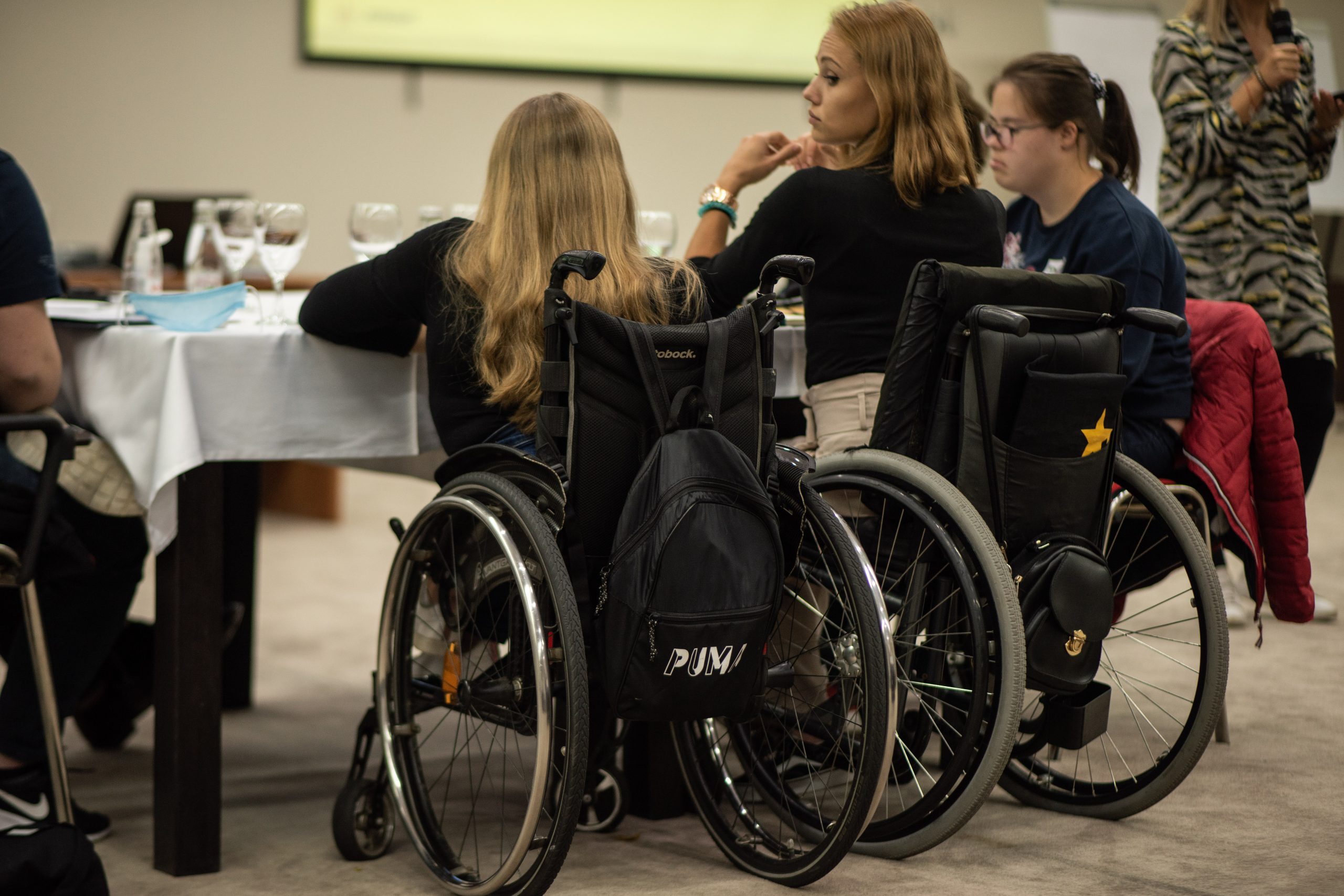 Två unga kvinnor i rullstol sitter bredvid varandra, vi ser deras ryggar