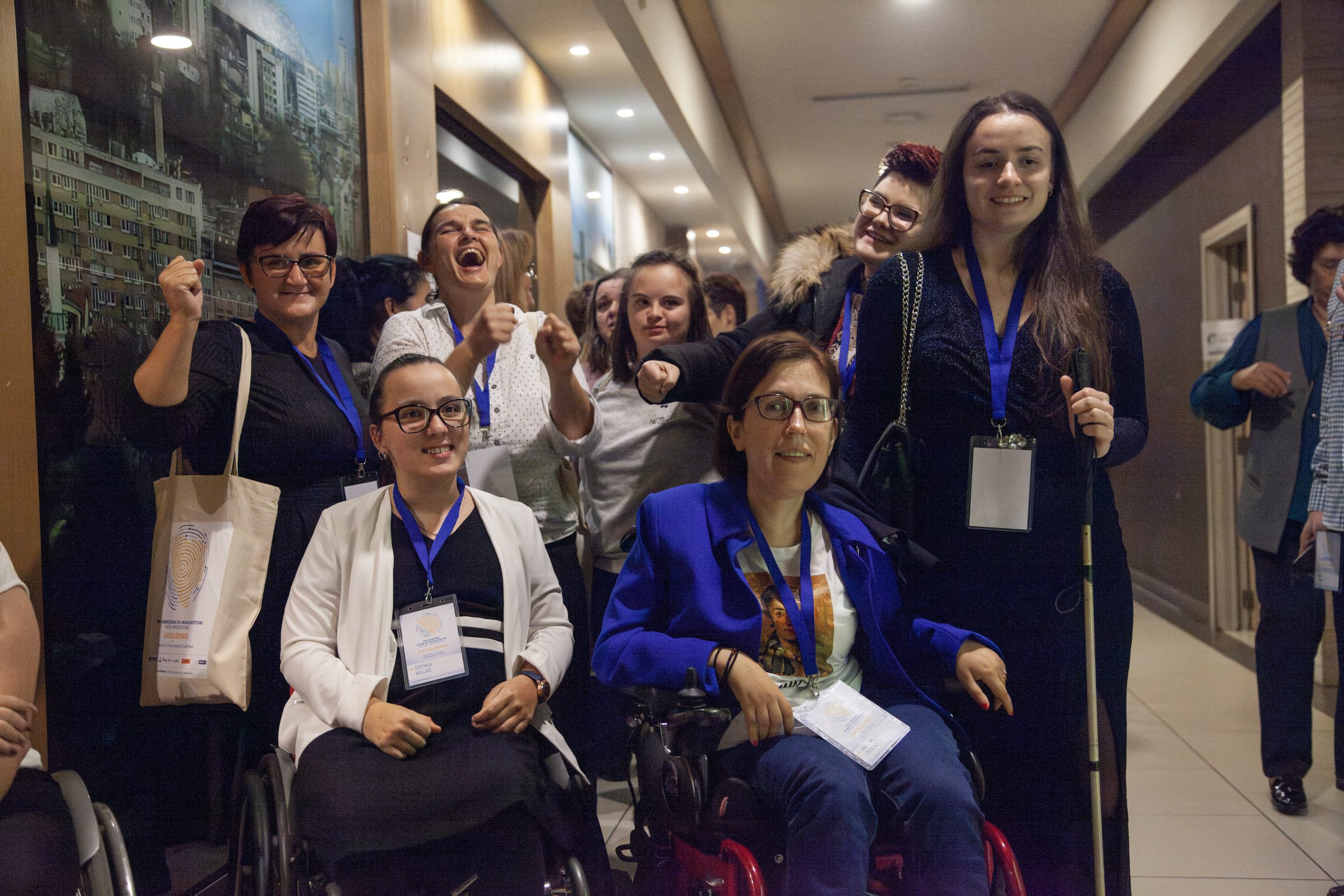 Sju kvinnor med olika funktionsnedsättningar står tillsammans och ler in i kameran.